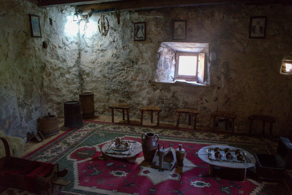 inside the lockin tower with stone walls and a mock set up of cups, albanian rugs and one or two windows