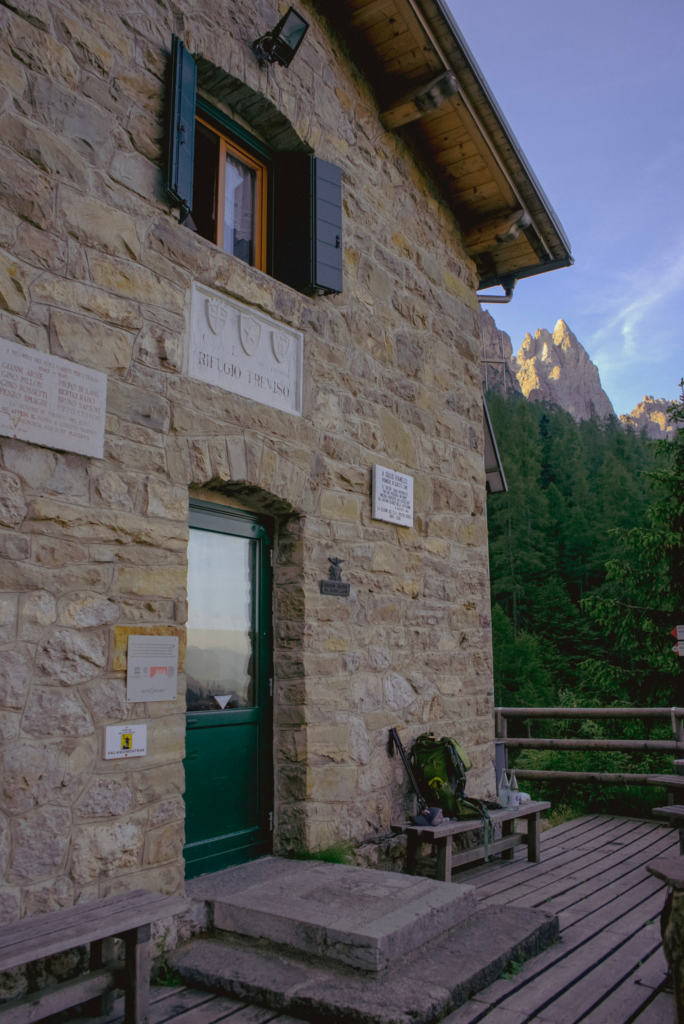 facade of Rifugio treviso that is made out of rock and has a green door.