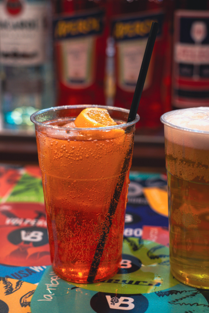A fizzy orange drink with a black straw in it otherwise known as an aperol spritz