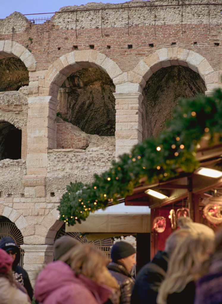 Verona Arena as the sunsets with the festive lights of a market stall in the corner