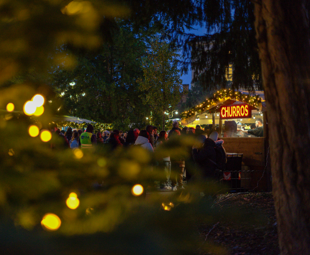 a blurry christmas tree in the foreground with a churros sign in the background
