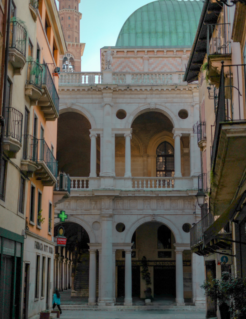 a narrow street view of the basilica palladia in Vicenza Italy with it's green rooftops