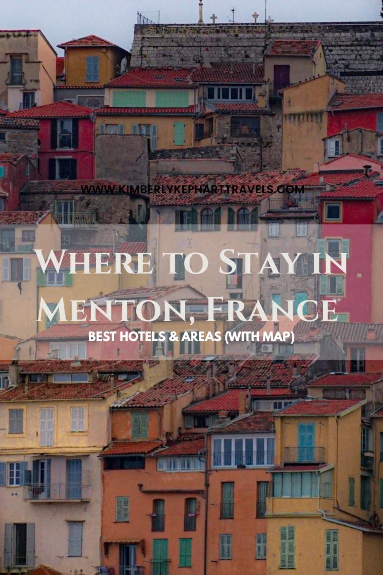 A photo with colorful houses in the background in pink, yellow beige and blue in Menton France with the words that say "WHERE TO STAY IN MENTON FRANCE"