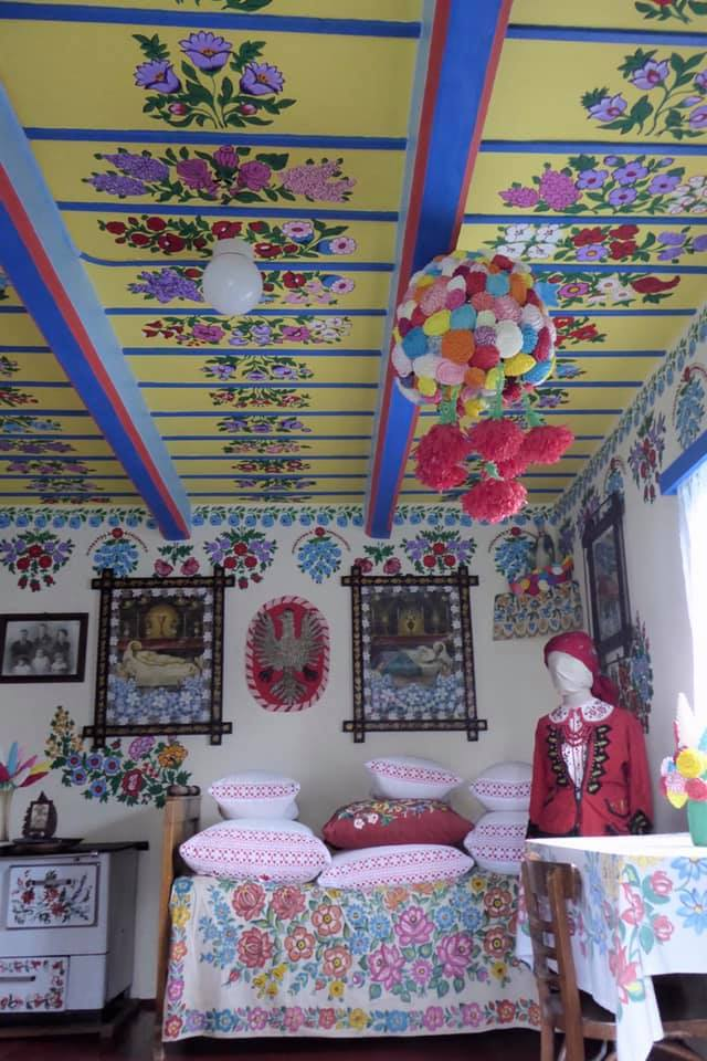 Felcijas house decorated with folk flowers represenative of Zalipie with the Polish eagle in the back to include bed linins