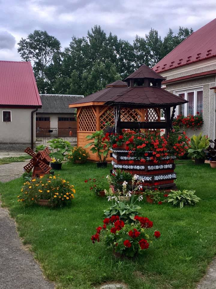 a brown well building with ornate flowers painted on in a garden in Zalipie Poland