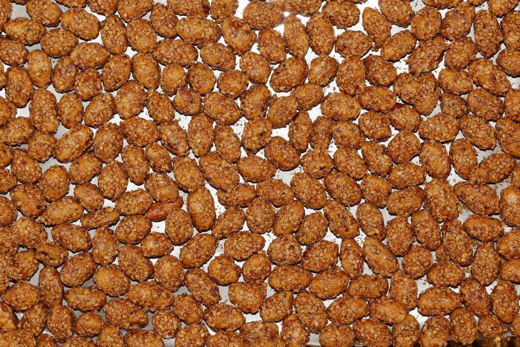 A detailed view of roasted candied almonds on a baking sheet, showcasing their crunchy texture.