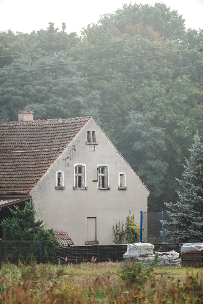 Historic rural house in Niegosławice, Poland surrounded by lush forest.