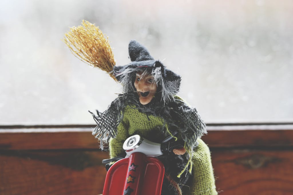 Colorful Befana witch figurine riding a toy scooter with a broomstick, capturing Italian folklore.