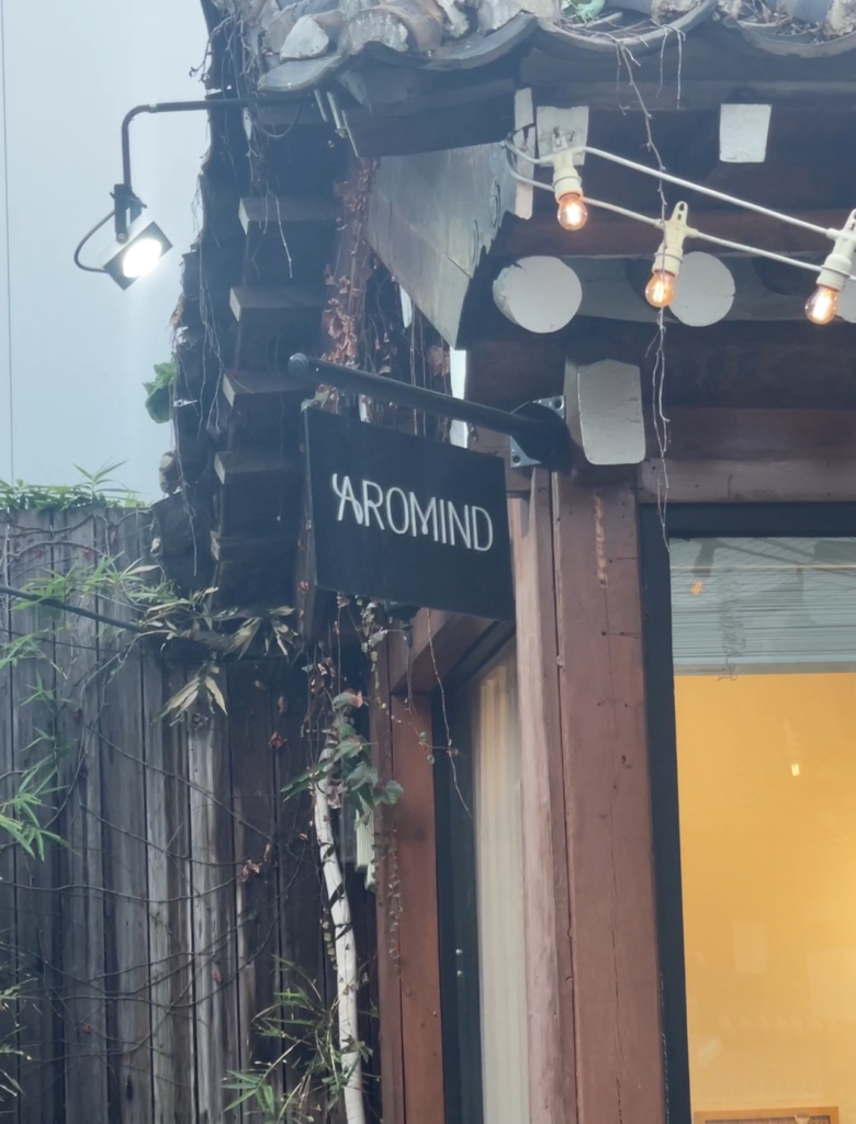 Exterior of AROMIND, a modern perfume boutique with a traditional Korean-style roof, wooden beams, and string lights. Visiting unique hanok-based shops like this is a relaxing and creative thing to do in Seoul South Korea. Image 2 alt text: