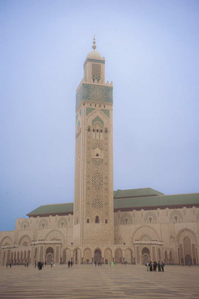 the ivory white tower of Hassan II Mosque stands against a misty background in Casablanca