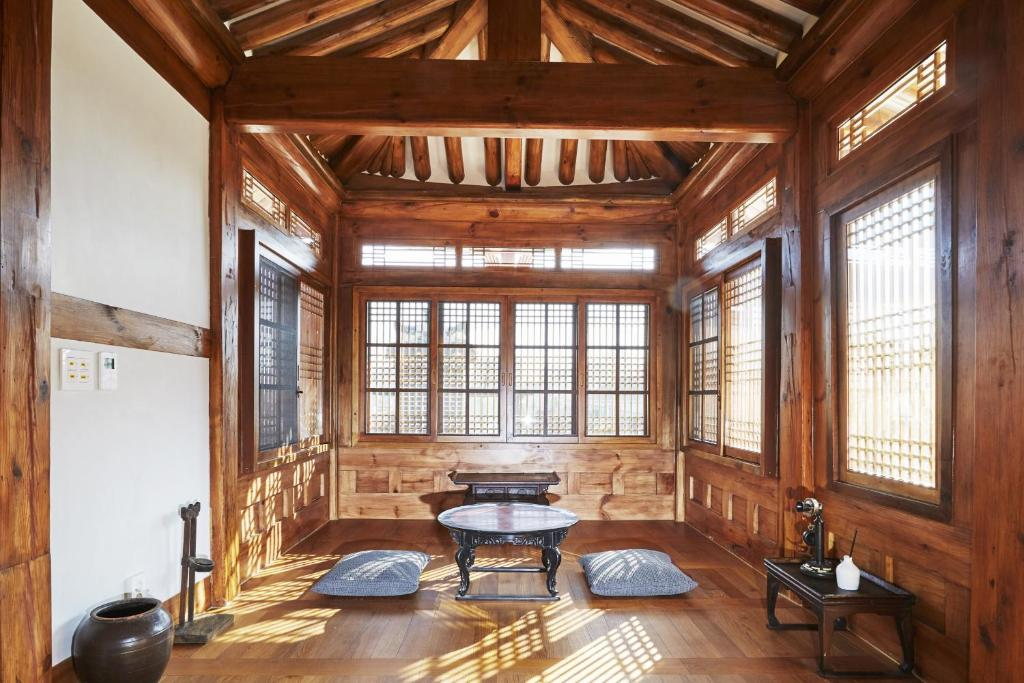 Interior of a traditional Korean hanok room with wooden lattice windows, floor cushions, and low tables in natural sunlight. This serene space reflects a unique accommodation style when deciding where to stay in Seoul South Korea.