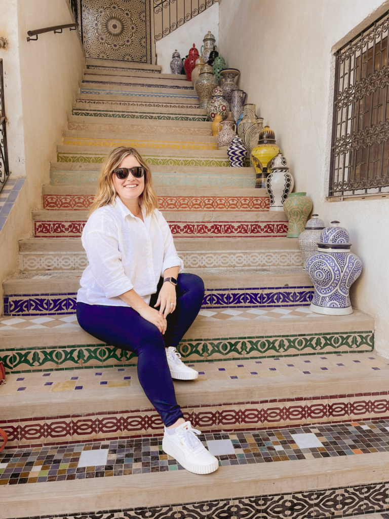 Woman in white shirt posing on a set of stairs in Fes Morocco