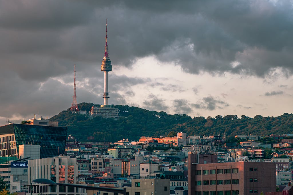 A stunning view of Seoul, South Korea's Namsan Seoul Tower surrounded by city buildings and dramatic clouds.