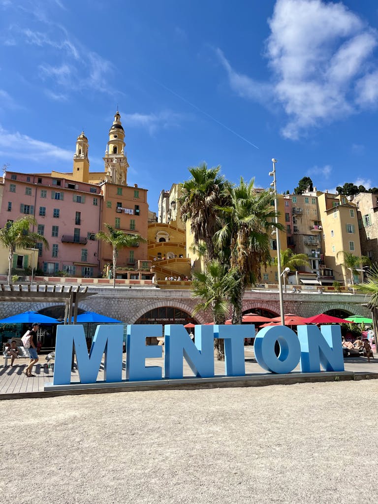 Bright sunny day in Menton with colorful buildings and palm trees.