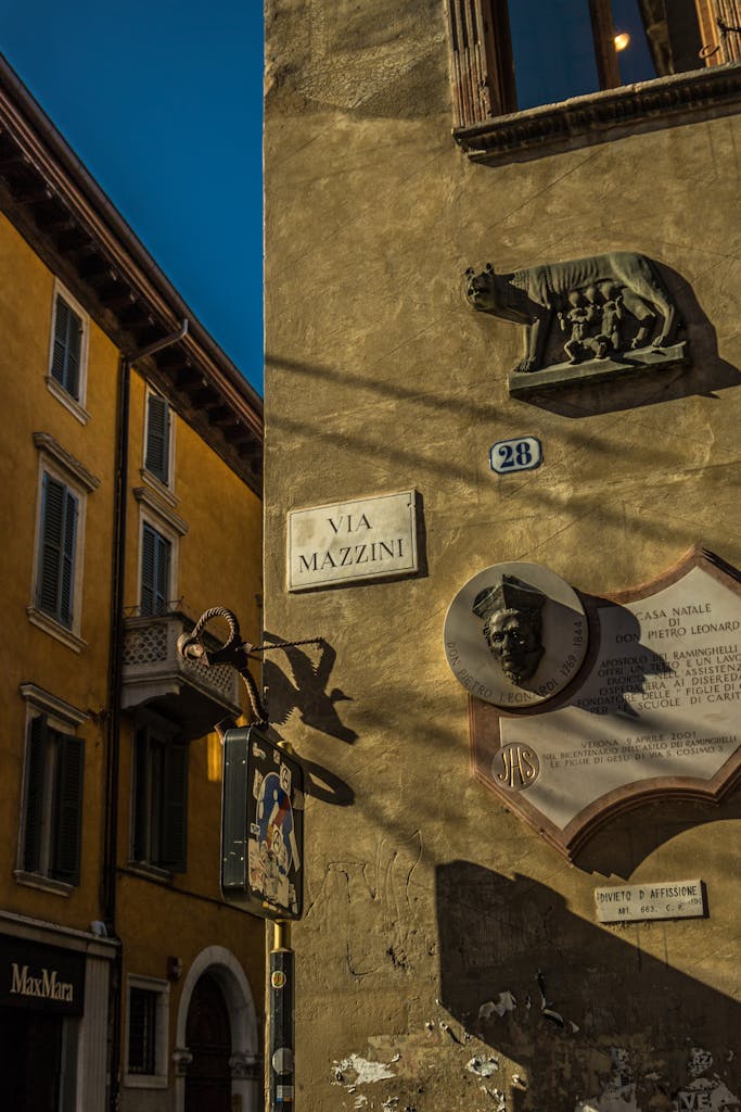 Historic corner on Via Mazzini, Verona with reliefs and building details.