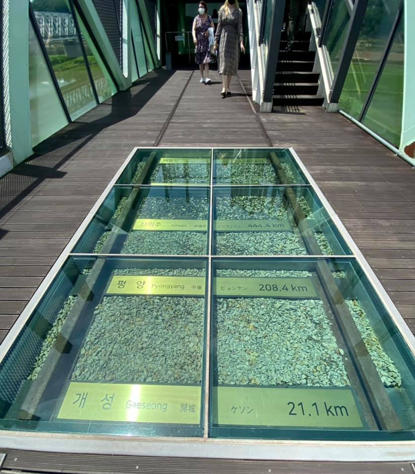 Glass floor display showing labeled stones and distances including Pyongyang 208.4 kilometers and Gaeseong 21.1 kilometers inside a DMZ observation building.