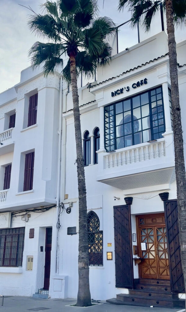 Outside of Ricks Cafe in Casablanca, Morocco feautreing a white facade and a palm tree near the front door