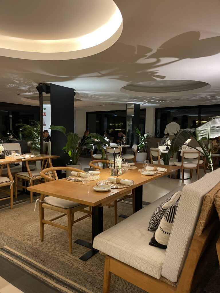 Stylish restaurant interior at Memmo Baleeira in Sagres with wooden tables, soft ambient lighting, and indoor plants creating a relaxed dining atmosphere for this Memmo Baleeira review.