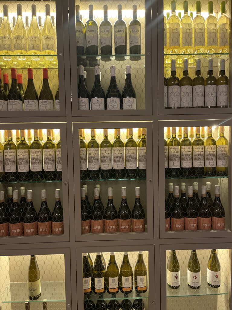 acklit display of wine bottles arranged on shelves behind glass at Memmo Baleeira in Sagres, highlighting the curated wine selection featured in this Memmo Baleeira review.