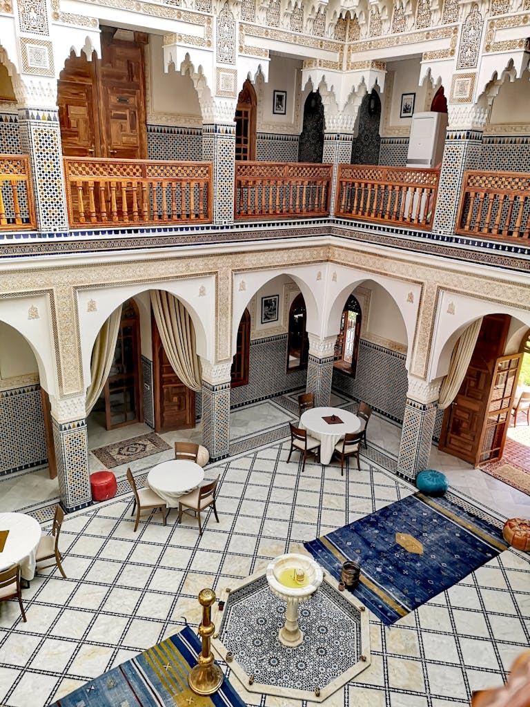 A beautifully decorated Moroccan riad interior showcasing ornate tile work and intricate wooden carvings.