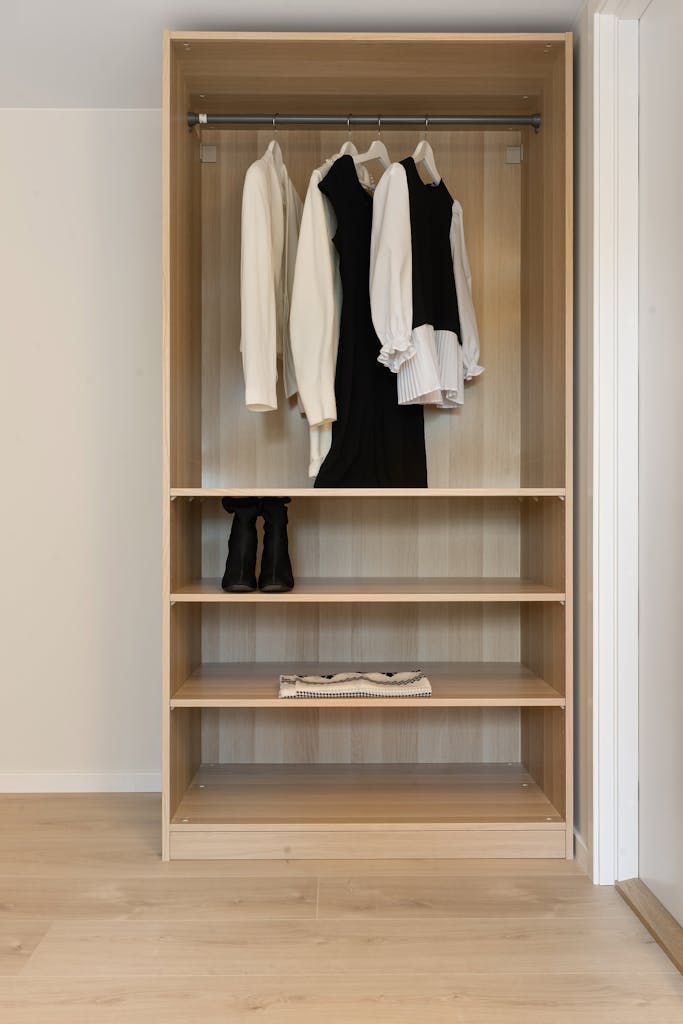 A neatly organized wooden wardrobe with a clothing rack and minimalist style.
