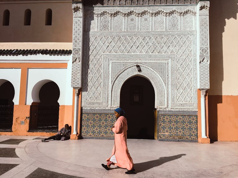 A person walks past an intricately designed Moroccan building in Marrakesh.