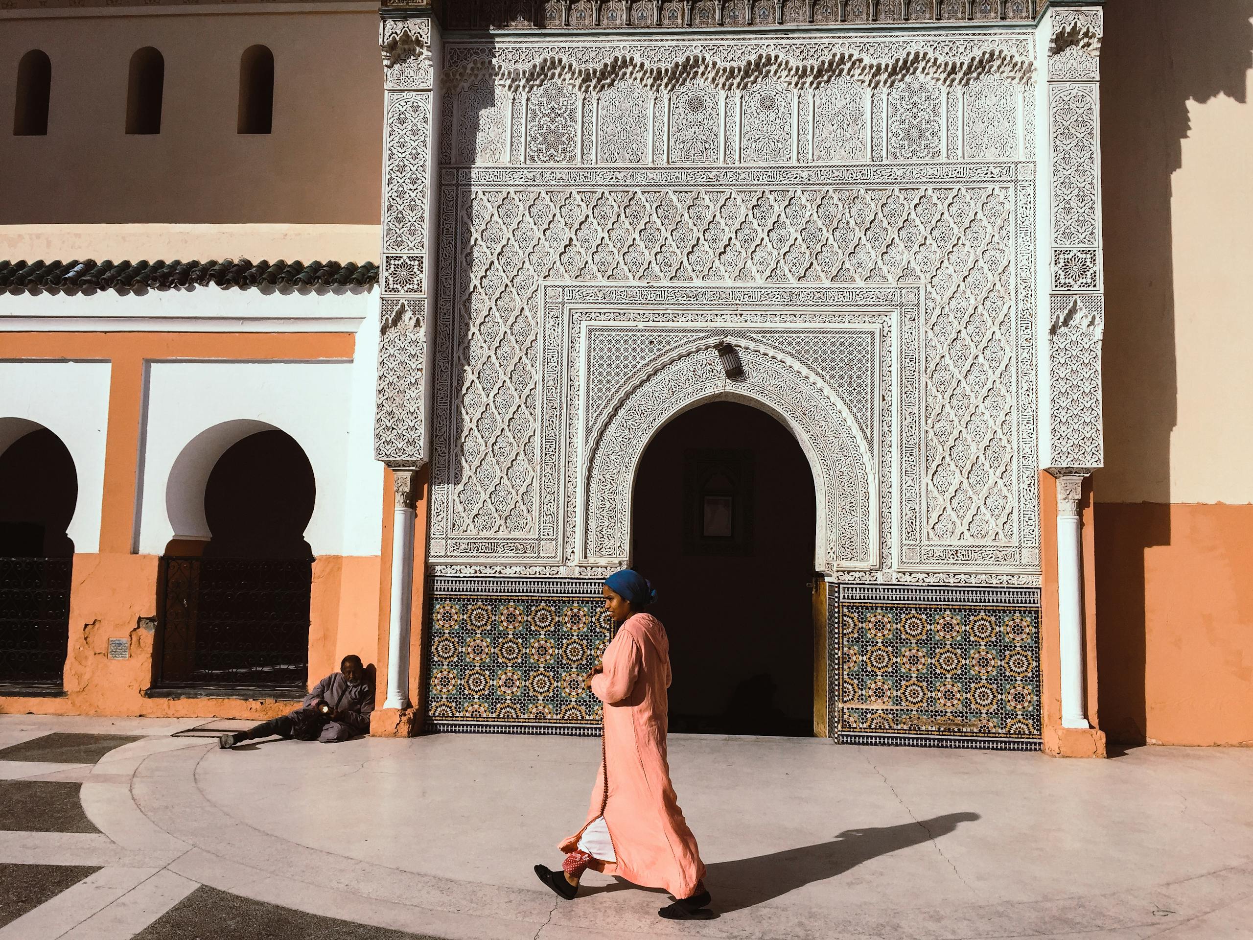 A person walks past an intricately designed Moroccan building in Marrakesh.
