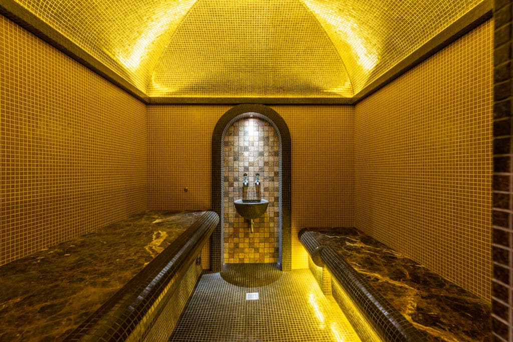 Elegant interior of a mosaic bathhouse with warm lighting and marble seats enhancing the luxurious atmosphere.