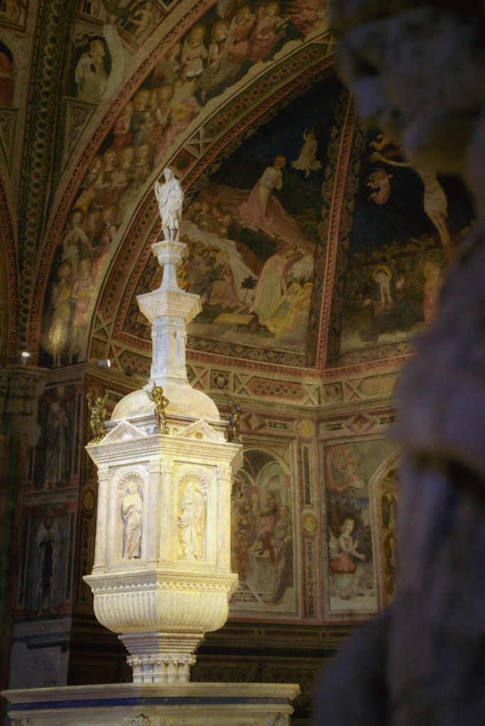 Elaborate pulpit inside the Siena Duomo surrounded by colorful murals and religious scenes. The detailed carvings and paintings reflect the artistic richness included in a 2 days in Siena itinerary.