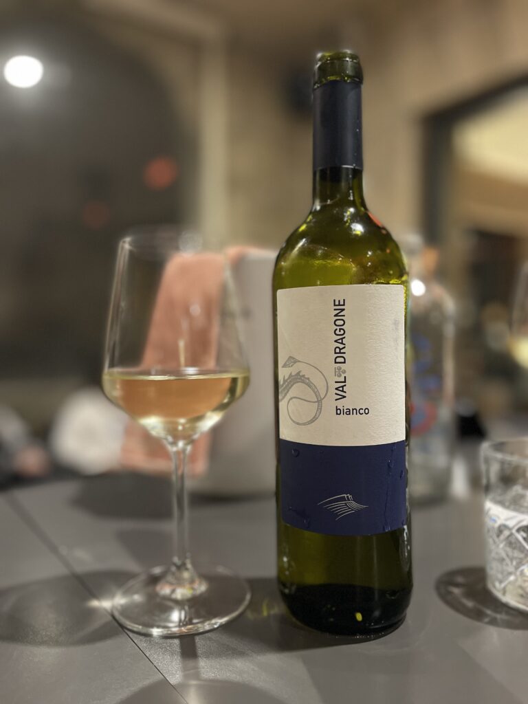 Bottle and glass of white wine labeled "VALDRAGONE bianco" on a La Loggia restaurant table with soft lighting, part of a dining experience during 2 days in San Marino.