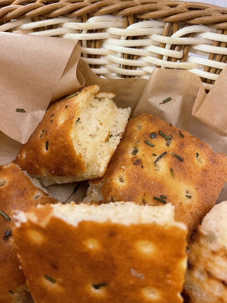 Basket of golden focaccia bread pieces topped with rosemary and olive oil, served warm as a starter during 2 days in San Marino.