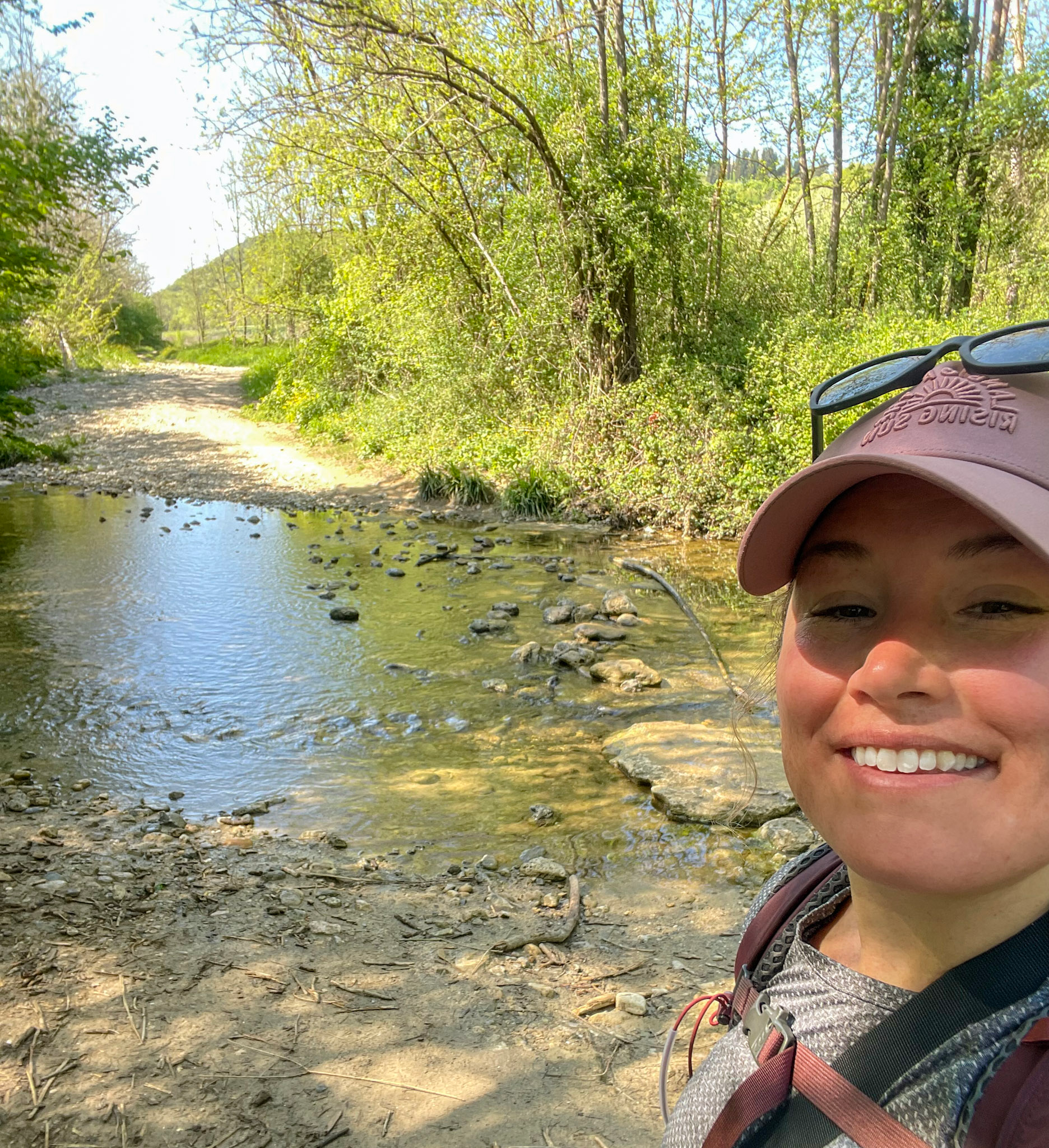 a woman smiling at the camera near a river crossing just outside of San Gimignano