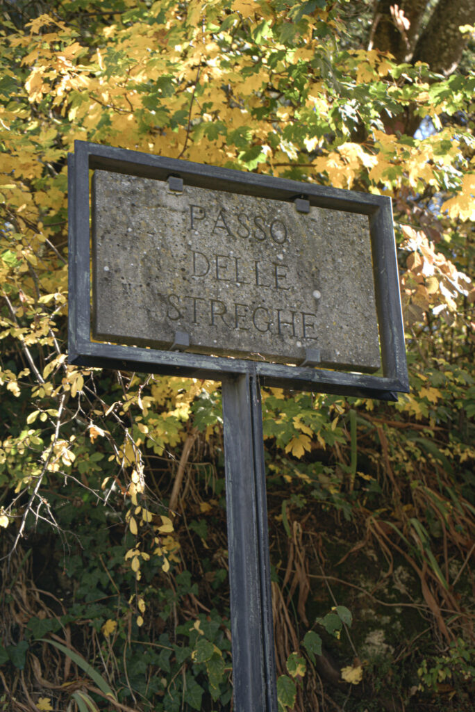 Stone sign surrounded by autumn leaves that reads "PASSO DELLE STREGHE" along a scenic walking path included in a 2 days in San Marino itinerary.
