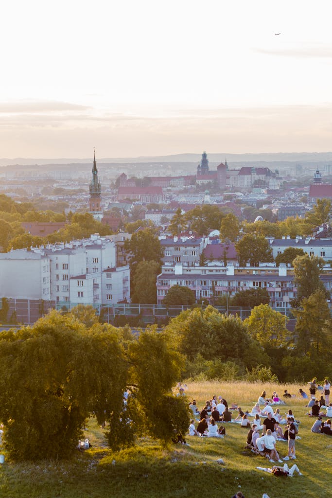 Enjoy a summer sunset view over Kraków with people relaxing in a park.
