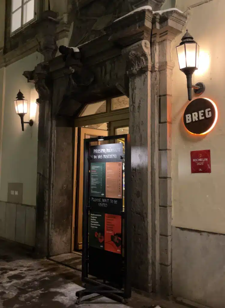Entrance to Breg restaurant in Ljubljana with the Michelin 2025 plaque visible on the stone facade at night
