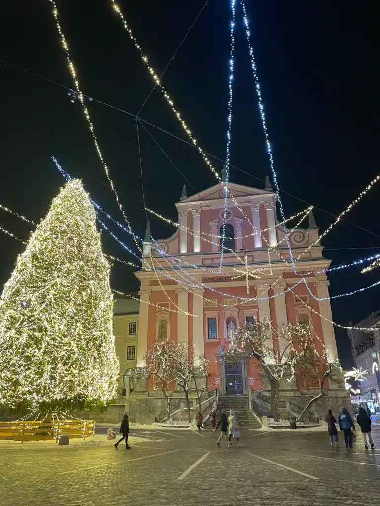 Preseren Square in Ljubljana at night in winter with Christmas tree and pink Franciscan Church of the Annunciation lit up