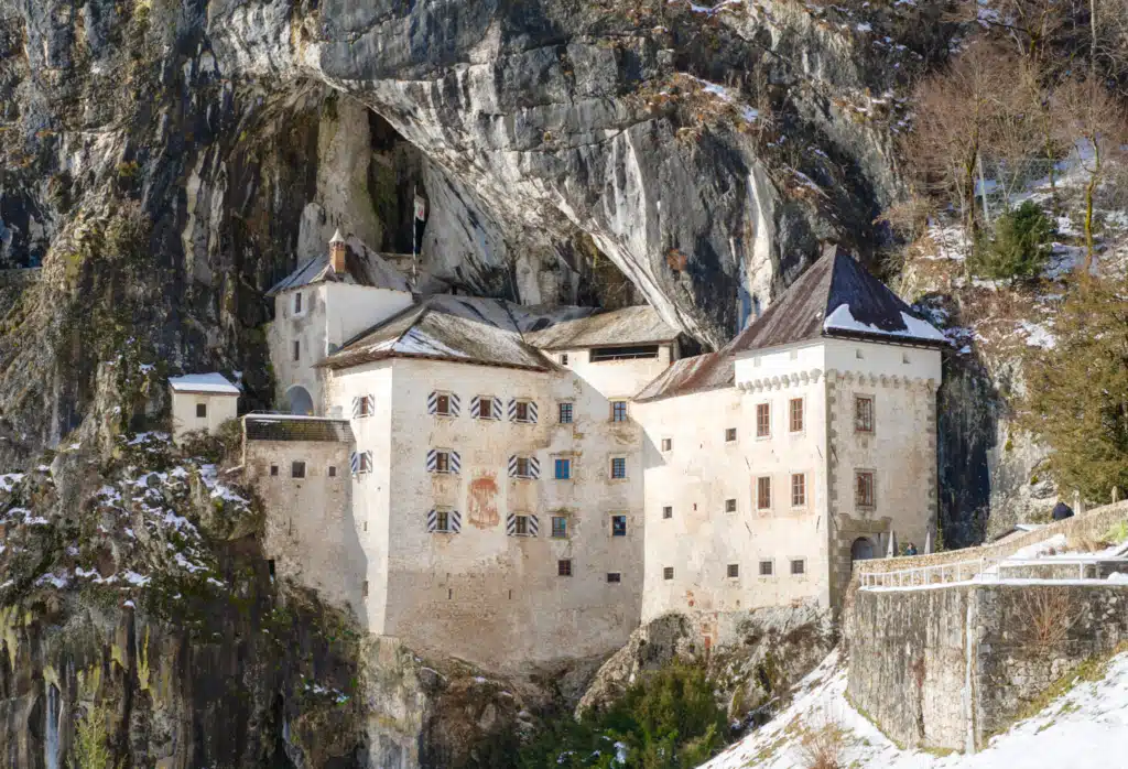 Predjama Castle in Slovenia built into the cave opening of a 123-meter cliff in winter with snow on the surrounding rocks