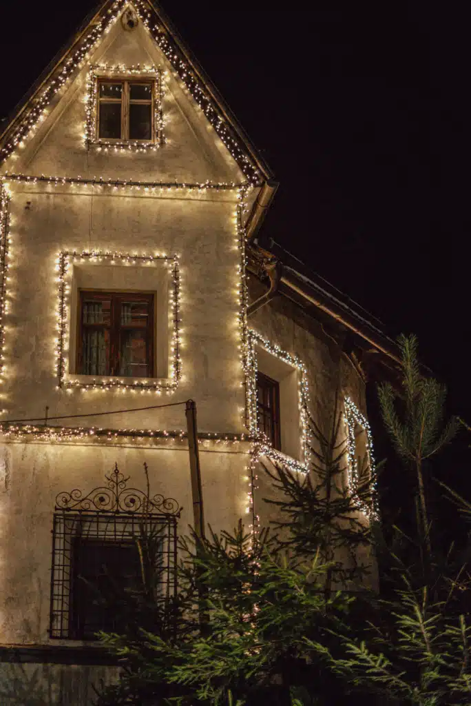 A traditional South Tyrolean house outlined in warm fairy lights around its windows and gable at night