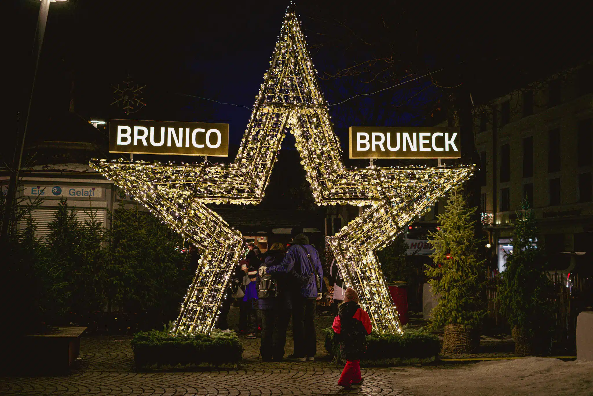 Illuminated star archway lit up at night with Brunico and Bruneck signs at the Christmas market entrance