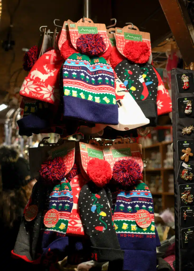 Stall of knitted pom-pom Christmas beanies and LED light-up hats at the Bruneck Christmas Market