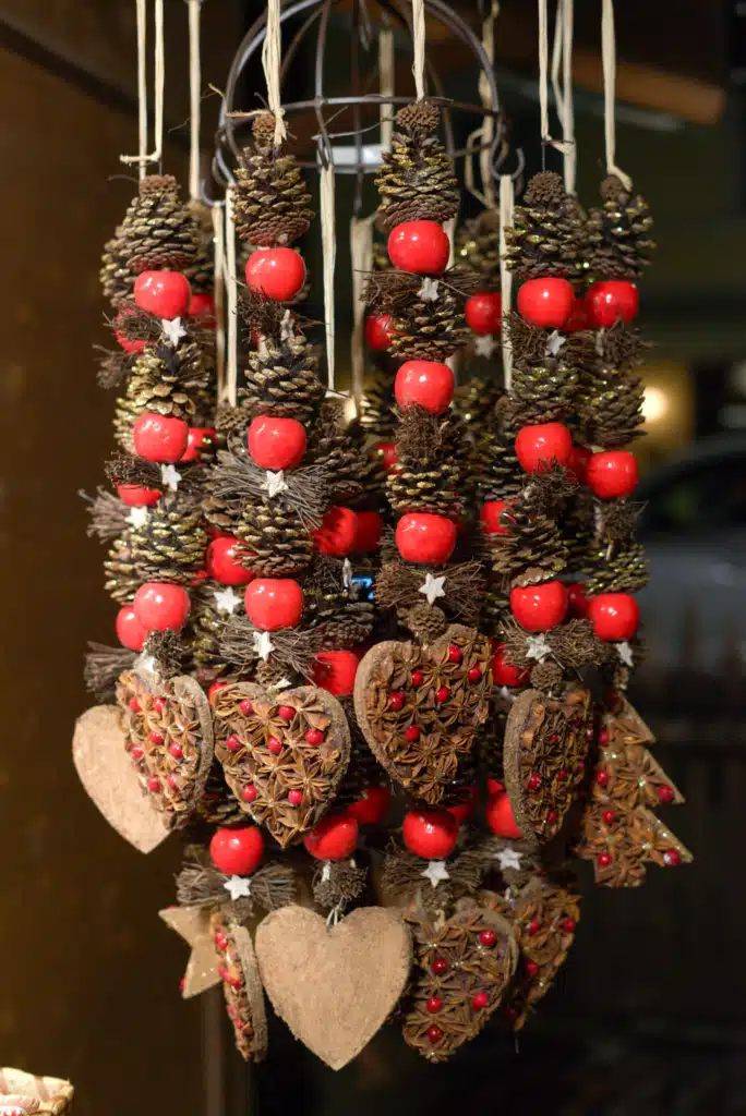 Handmade natural Christmas ornaments — pinecones, red berries, and star-anise hearts — hanging at a Bruneck market stall