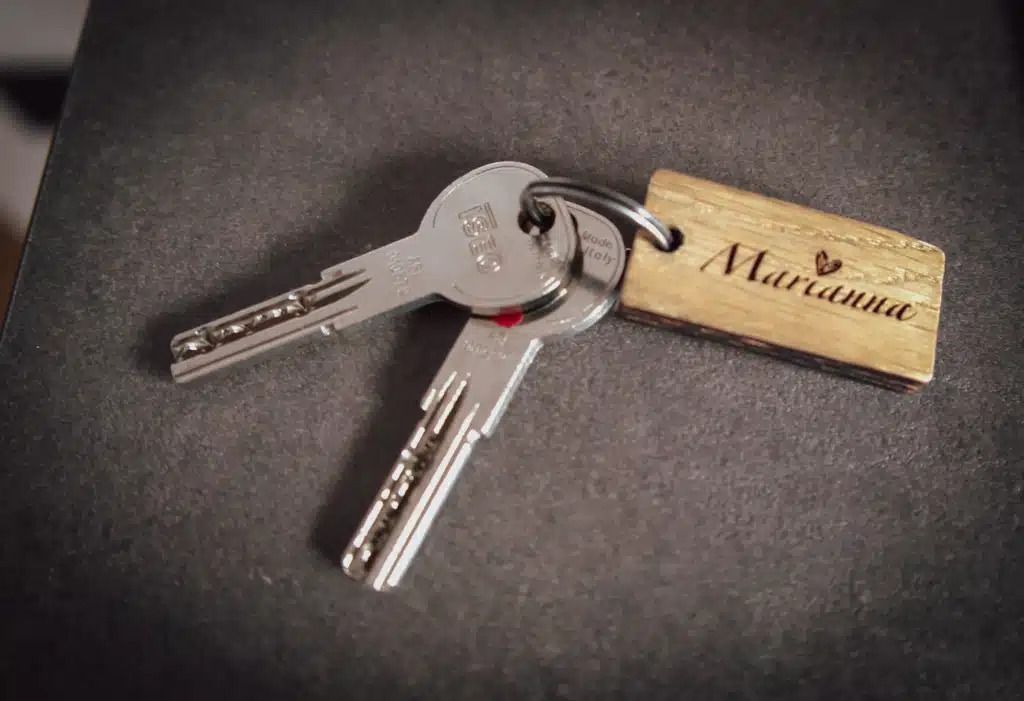 Apartment keys with a wooden "Marianna" keychain resting on a dark countertop at Appartements Hofer in Dobbiaco.