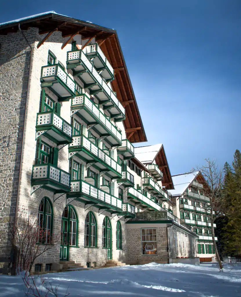 Historic alpine grand hotel with tiered green-and-white balconies in the snow at Lago di Braies (Pragser Wildsee), winter.