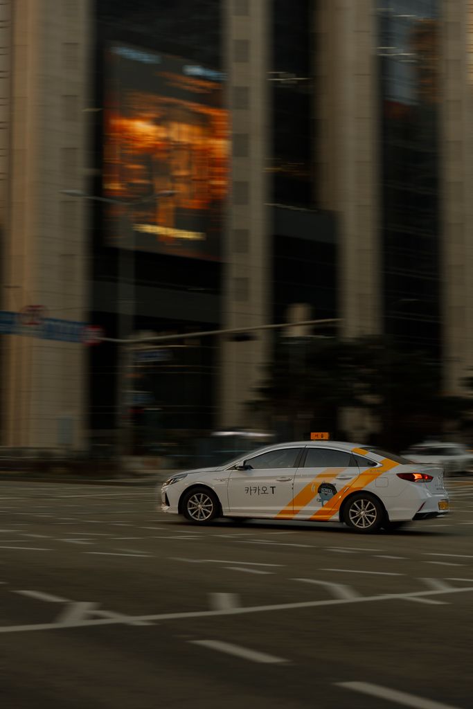 A taxi speeds through a bustling city intersection, capturing the essence of urban life.
