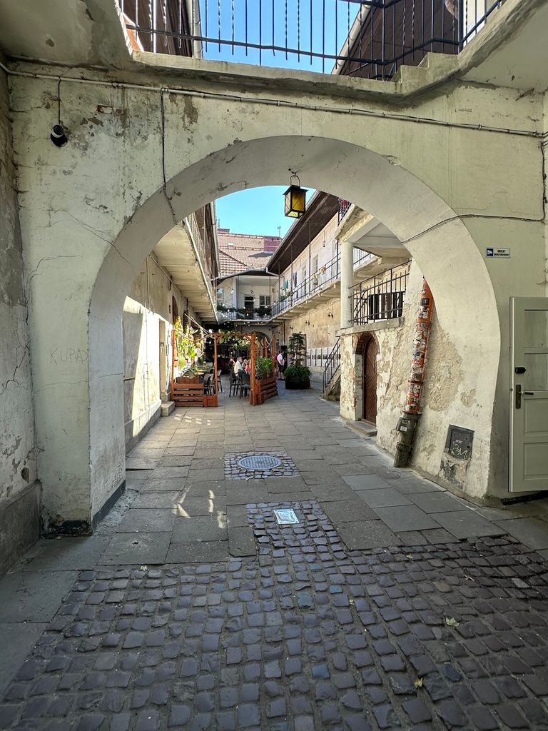 Scenic view of historic Kraków courtyard with archway and cobblestone path, exuding old-world charm.