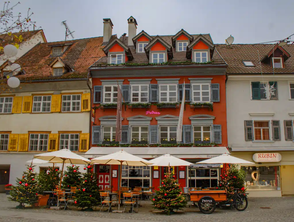 Red Petrus café building with Christmas trees and outdoor seating in Bregenz