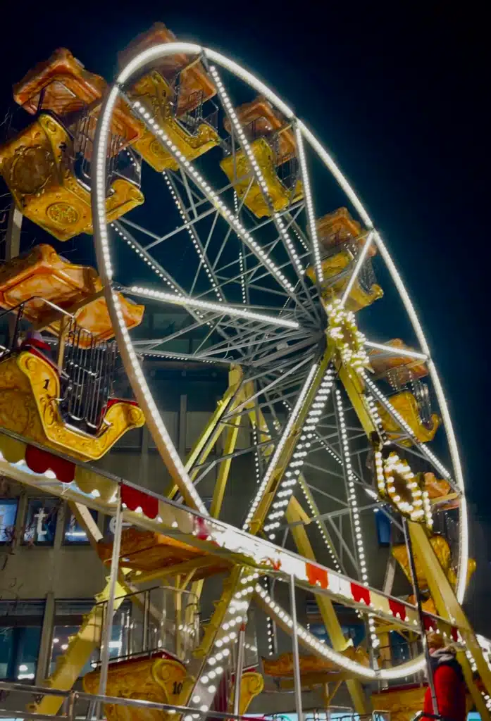 Illuminated Ferris wheel with gold gondolas at Bregenz Christmas market at night