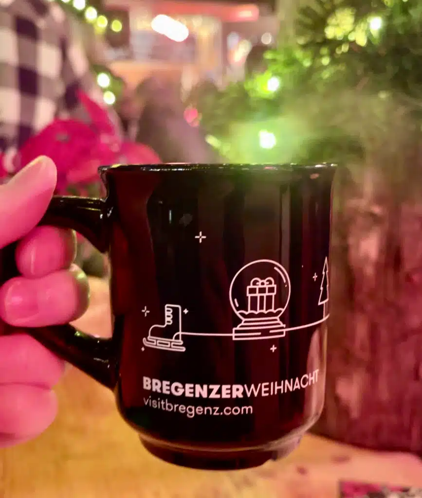 Hand holding Bregenzerweihnacht mulled wine mug at Bregenz Christmas market