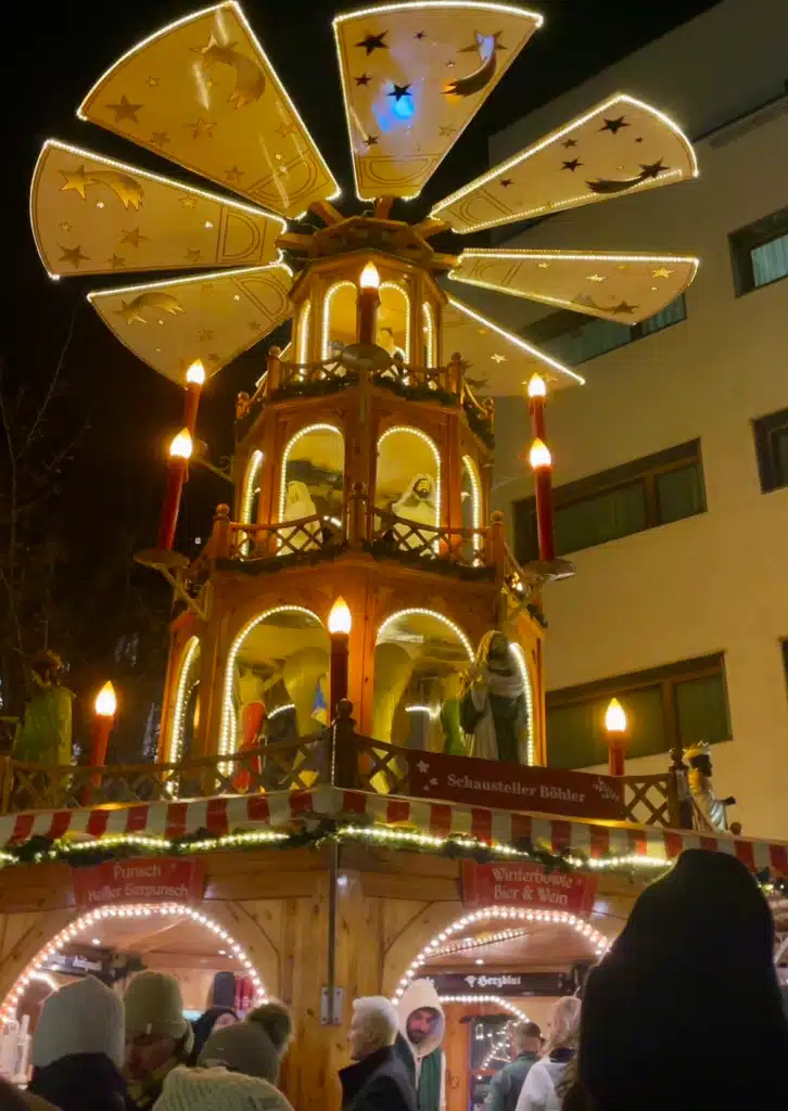 Wooden Christmas pyramid with nativity figures and star panels, Bregenz market stall