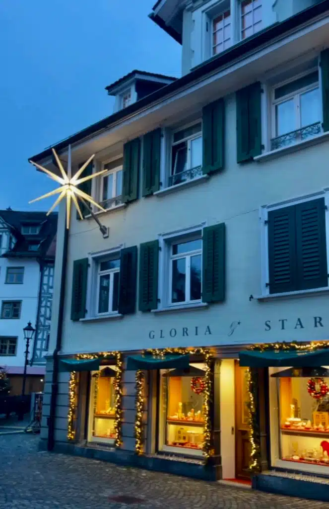 Illuminated Christmas star on historic shopfront in St. Gallen old town at dusk